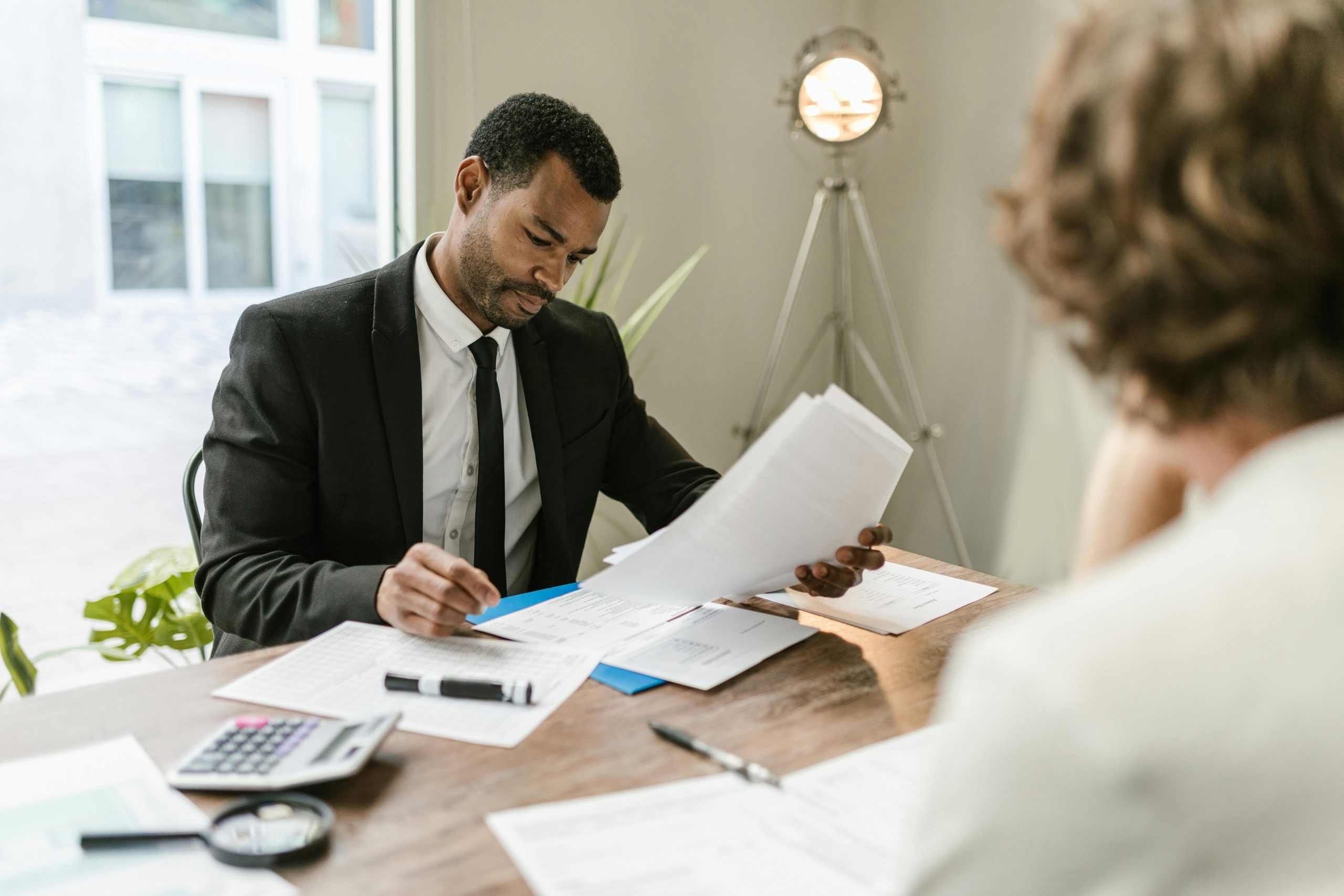 A banker in a black suit is reviewing a loan application in an office.