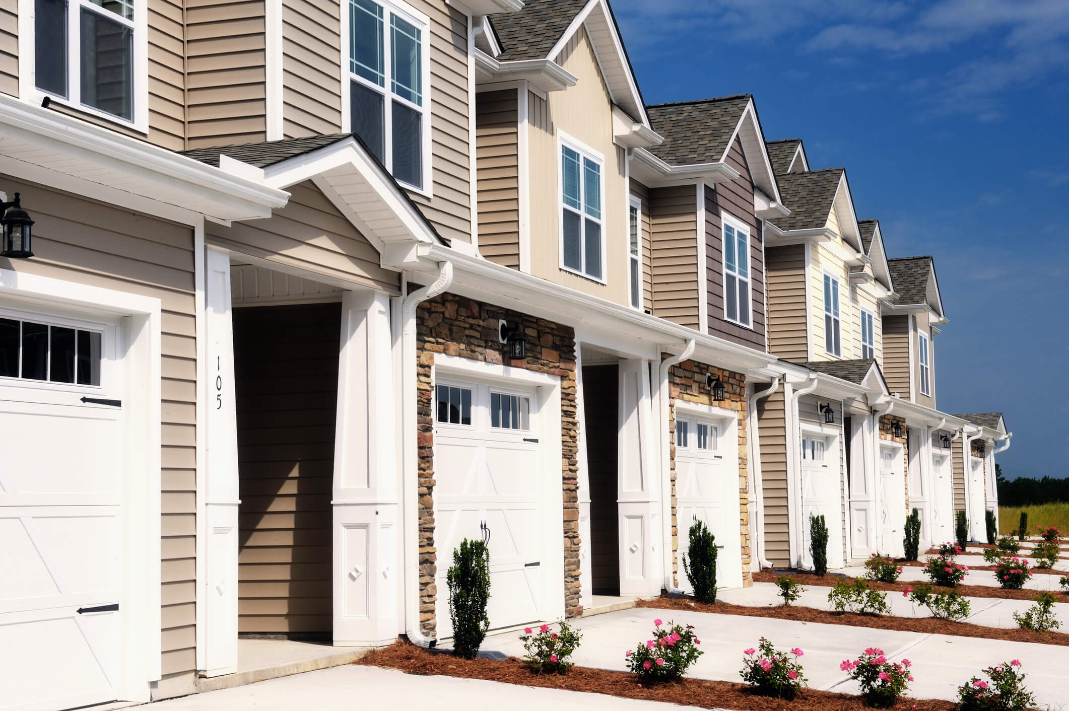 Row of two-story townhomes with white garages can become rental property through a DSCR loan.