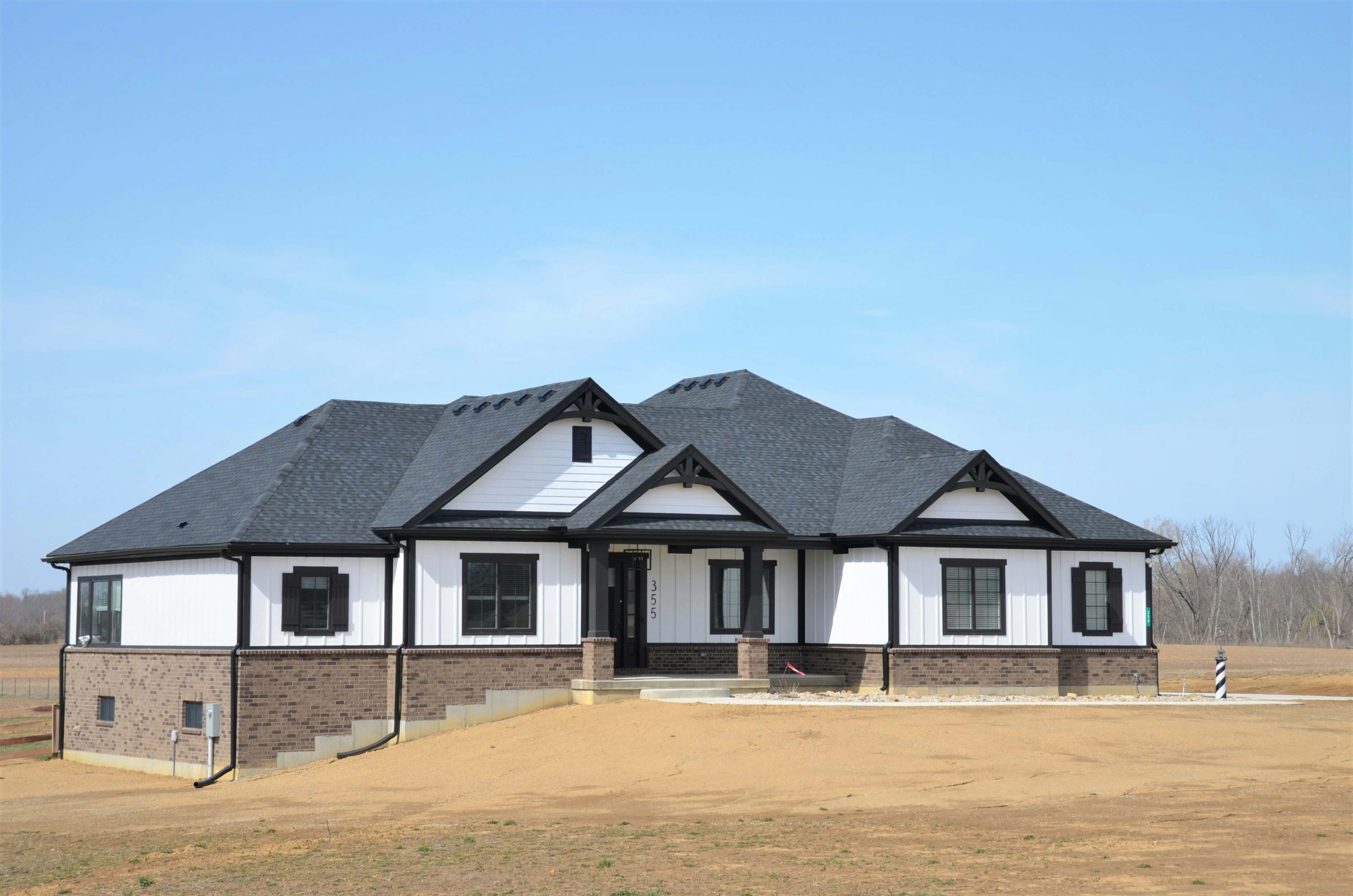Newly built home with white siding, brick foundation, and dark roof, illustrating an article comparing new homes vs. existing homes.